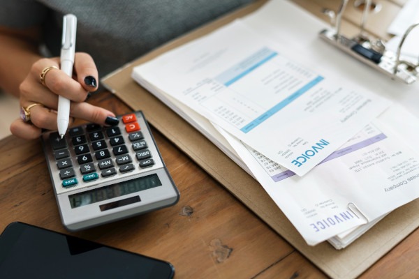 Invoice and calculator on table - Avoid These 5 Invoicing Mistakes