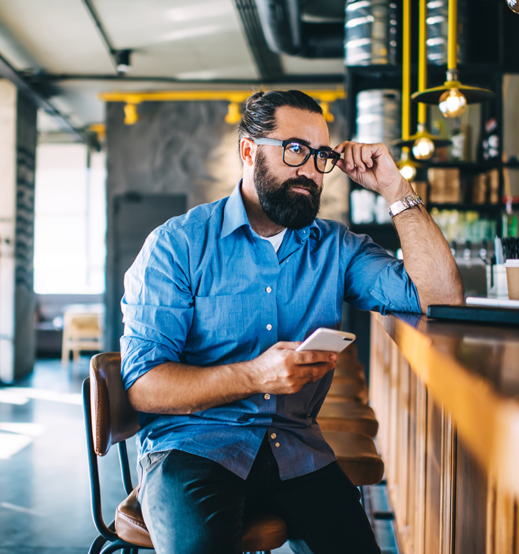 Small business owner taking a business call on his smartphone while working remotely.