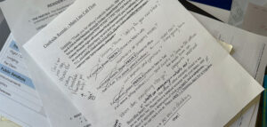 Alt Text: A printed customer service call flow document for Creekside Rentals on a messy desk, covered in handwritten notes identifying routing problems and unmonitored voicemail traps.